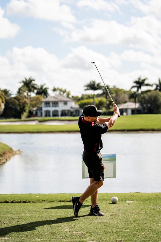 A man swinging at a golf ball on the course.