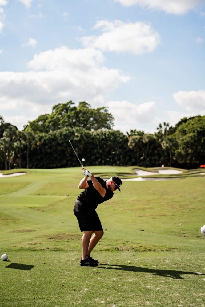A man swinging at a golf ball on the course.
