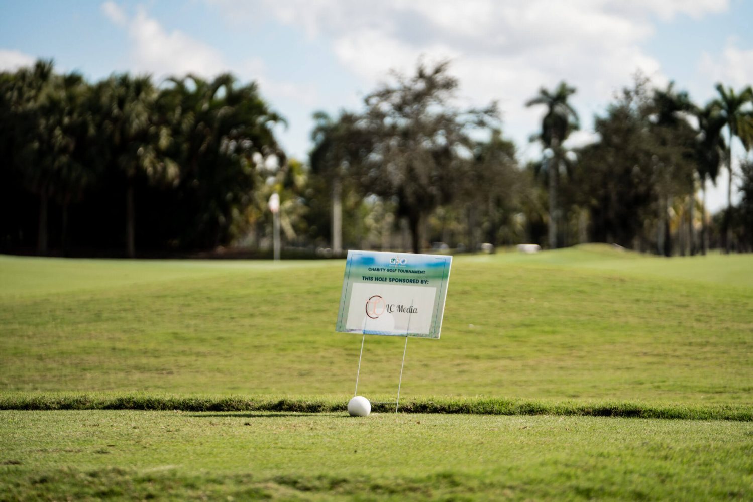 A sign is posted on the grass near a ball.