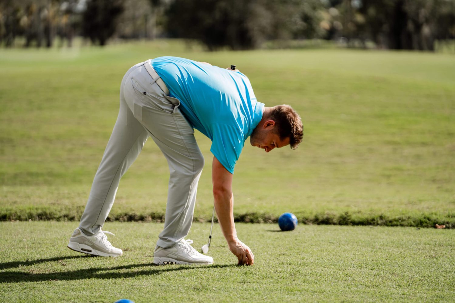 A man in blue shirt playing golf on green.