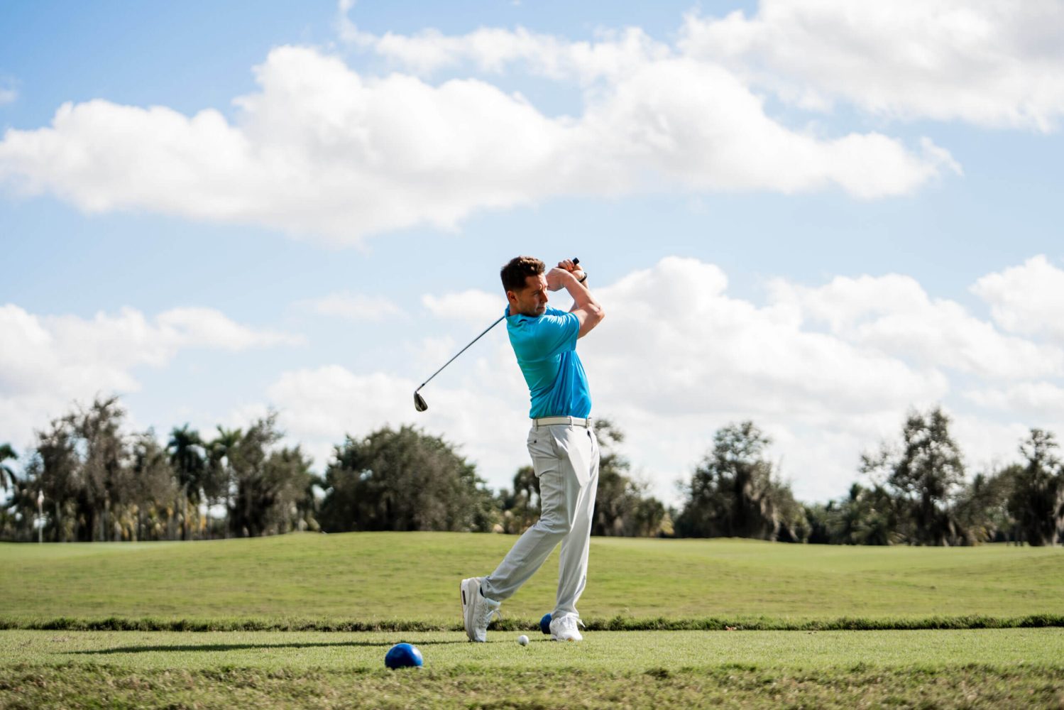 A man swinging at the golf ball on a course.