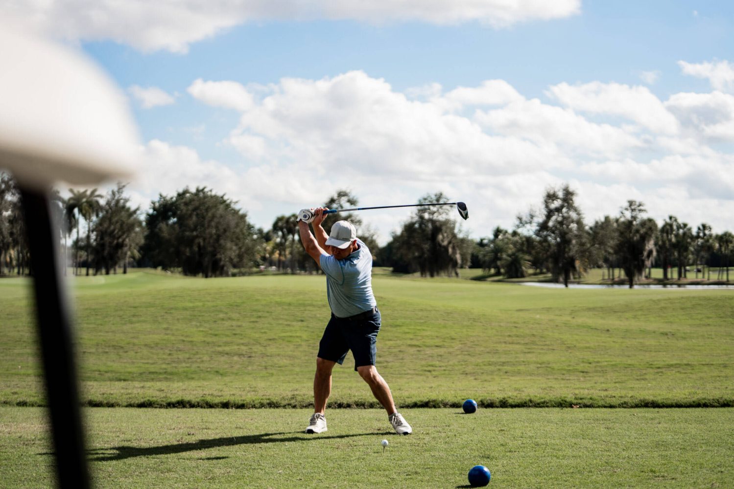 A man swinging at a golf ball on the green.