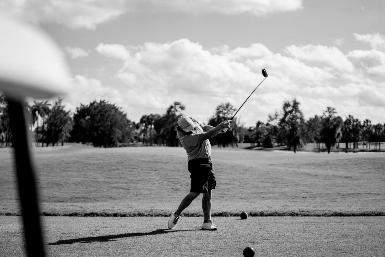 A man swinging at a golf ball on the course.