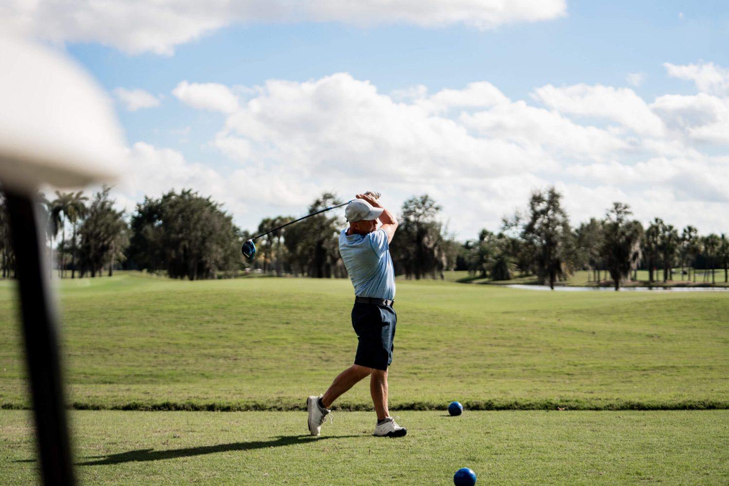 A man swinging at a golf ball on the green.