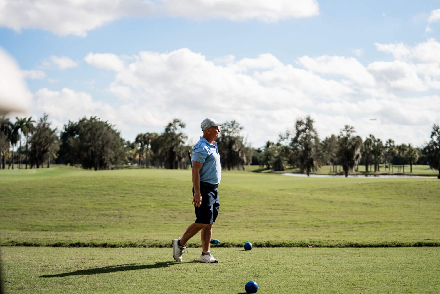 A man in blue shirt and shorts playing golf.