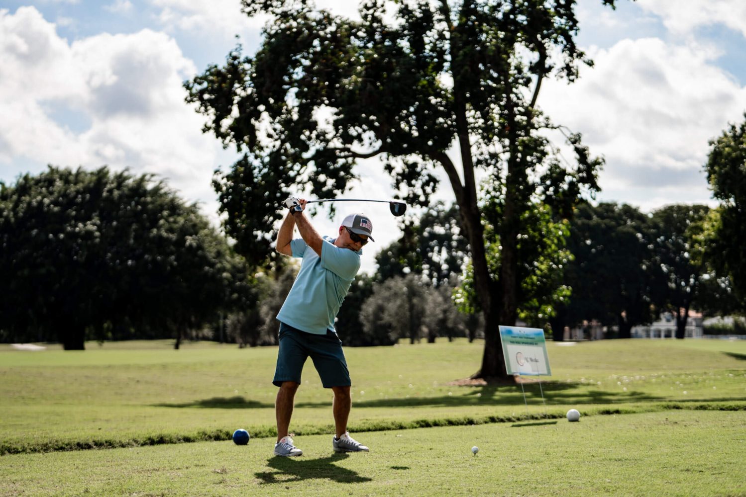 A man swinging at a golf ball on the green.