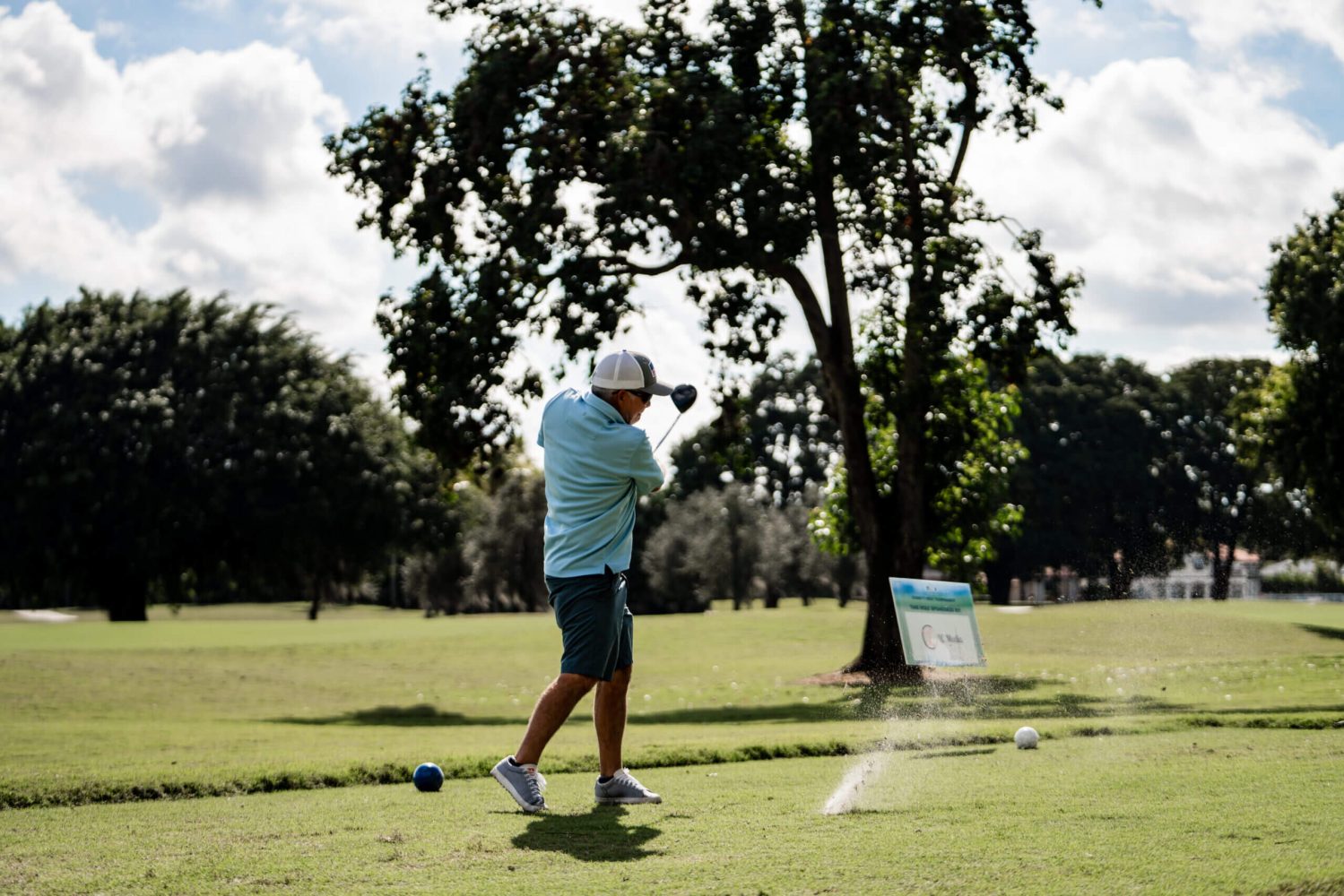 A man swinging at a golf ball on the green.