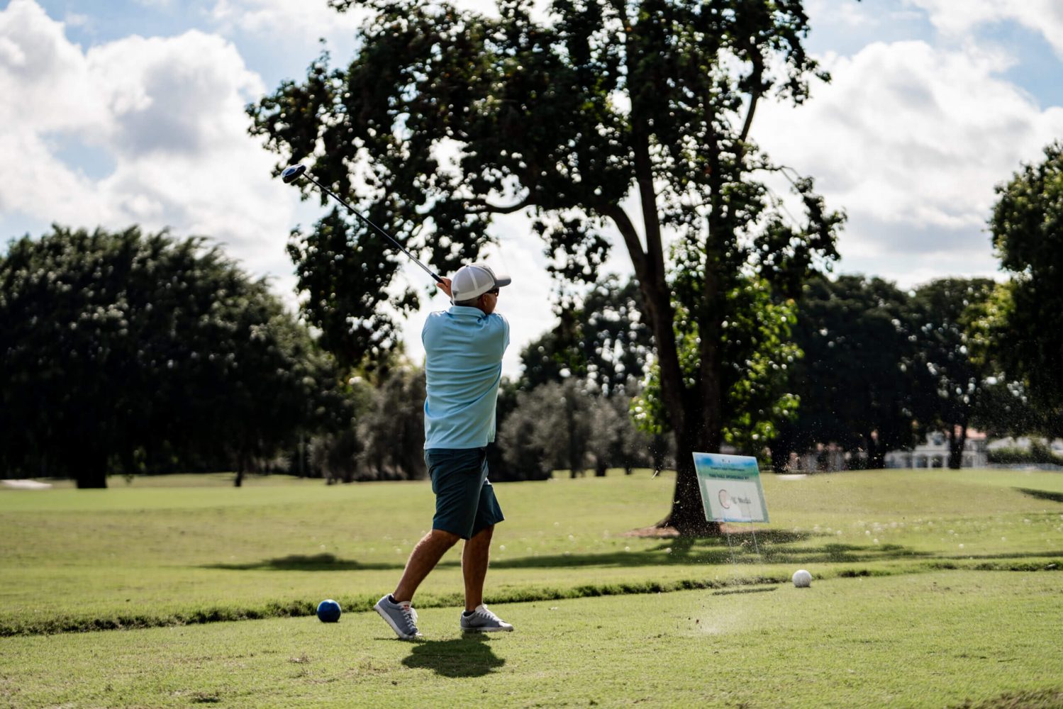 A man swinging at a golf ball on the green.