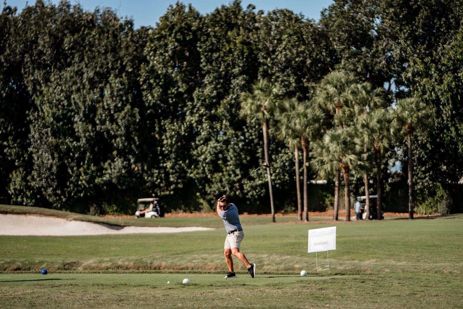 A man swinging at a golf ball on the green.