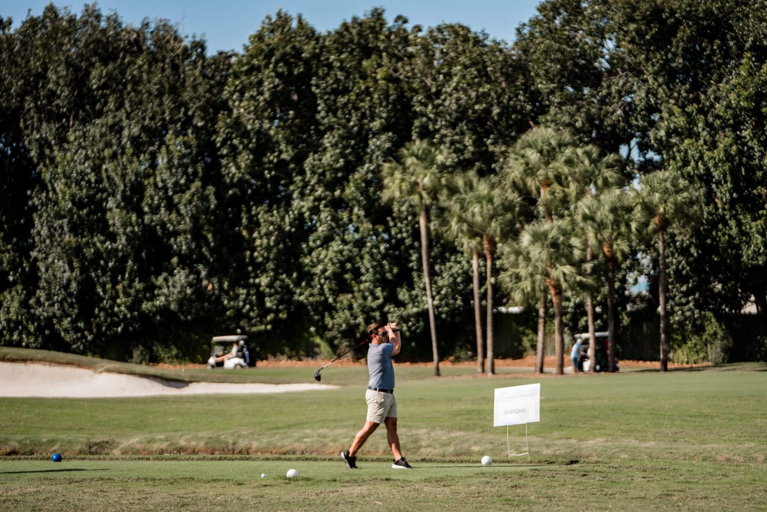 A man is swinging at the golf course