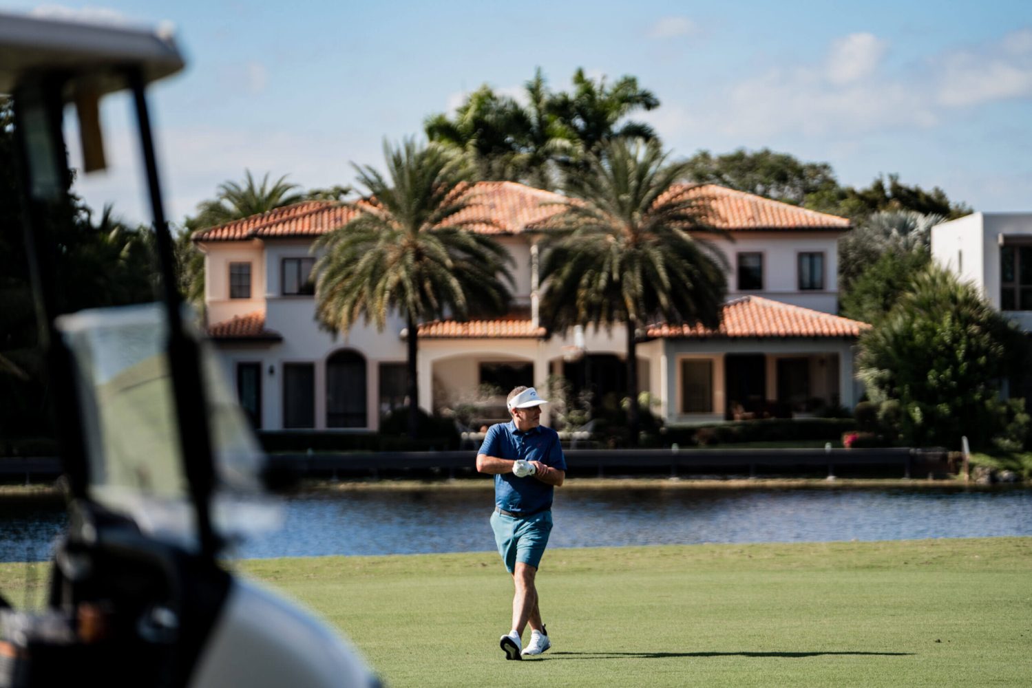 A man is walking across the grass on a golf course.