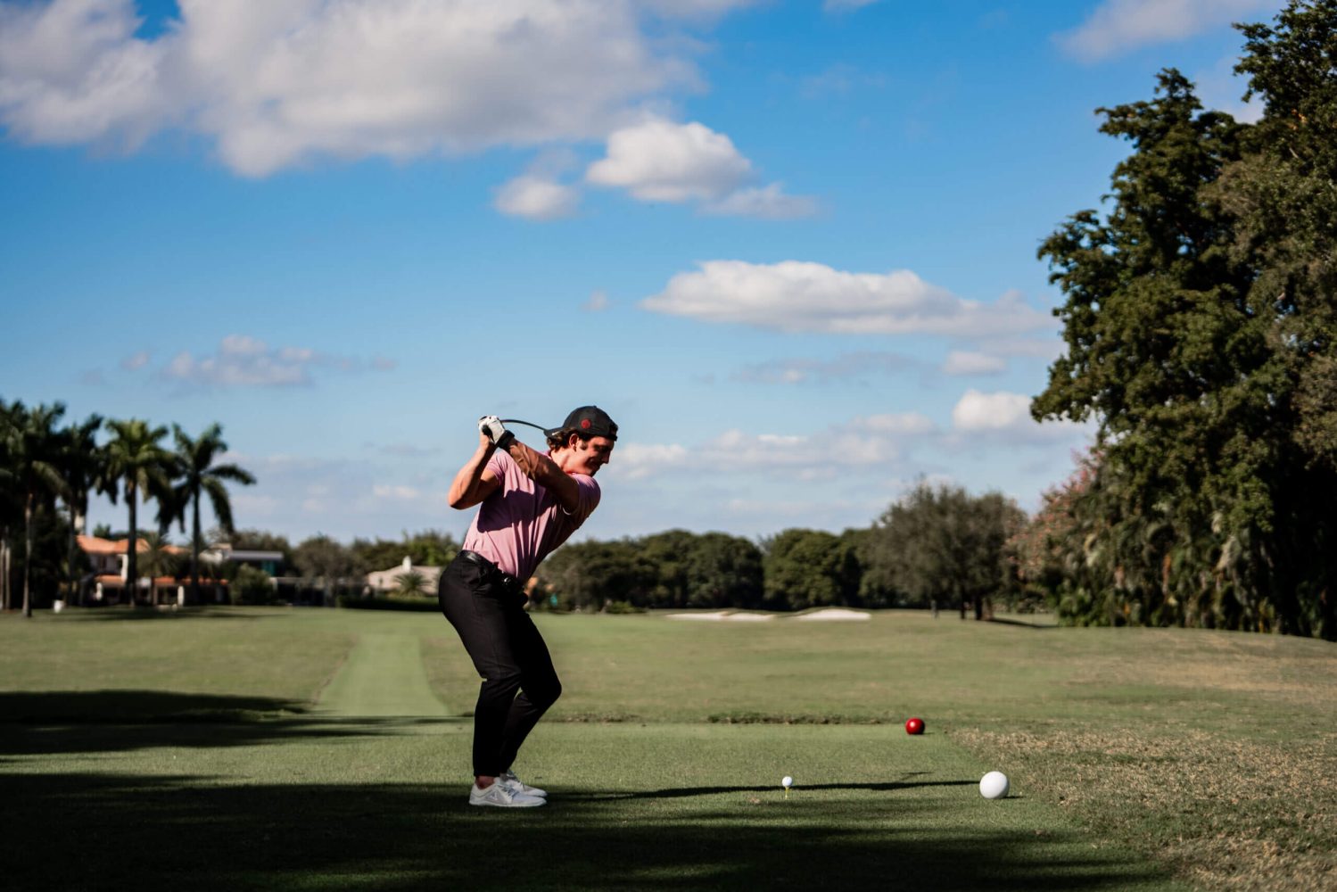 A man swinging at a golf ball on the green.