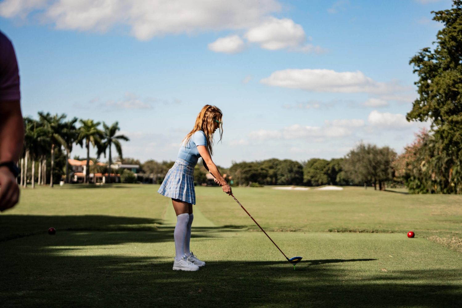 A girl in blue dress holding a golf club.