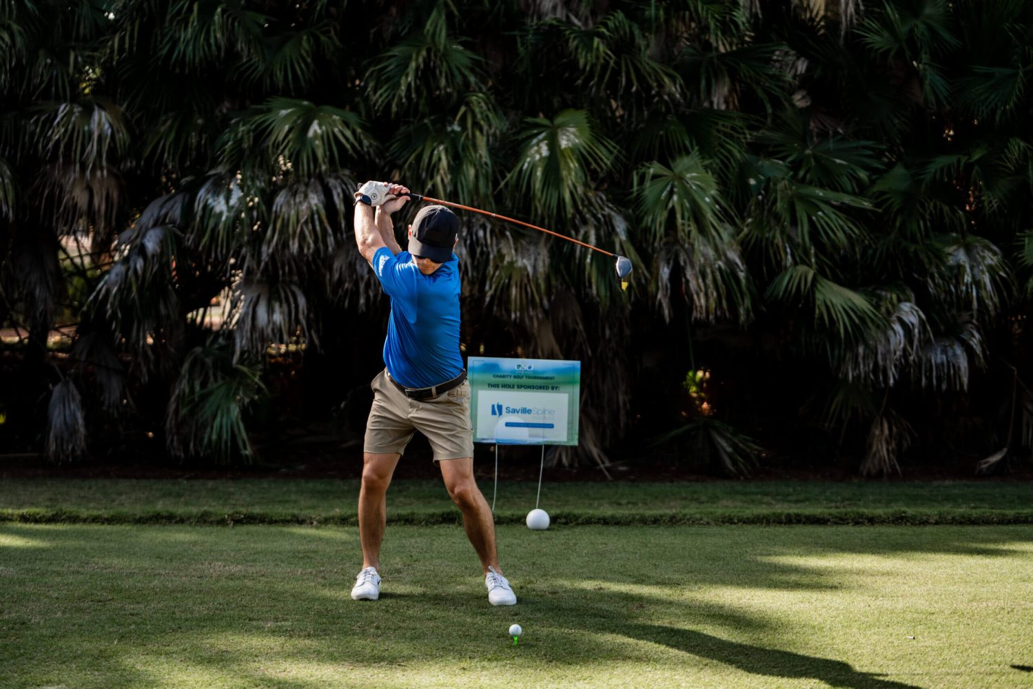 A man swinging at a golf ball on the green.