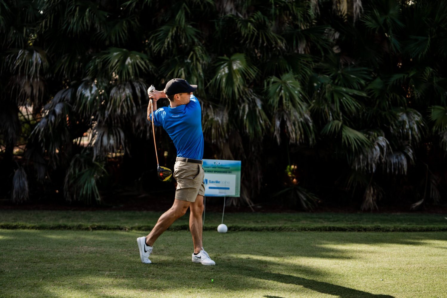 A man swinging at a golf ball on the green.