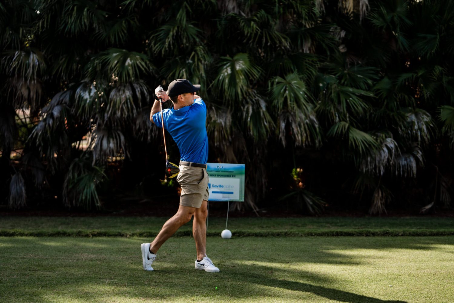 A man swinging at a golf ball on the green.
