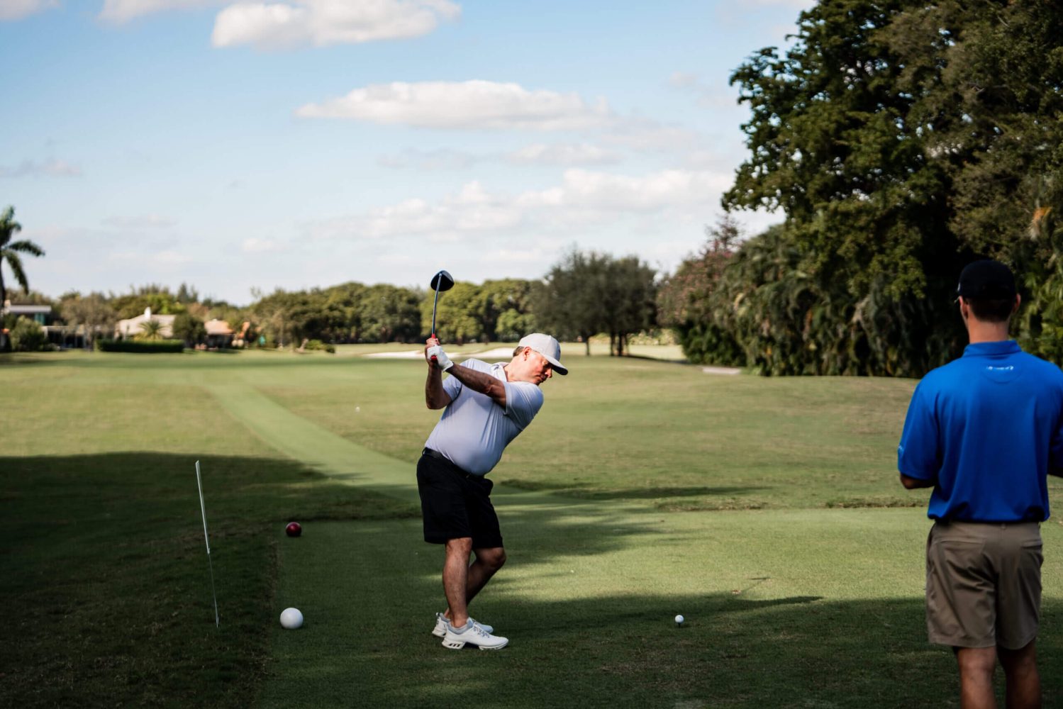 A man swinging at a golf ball on the green.
