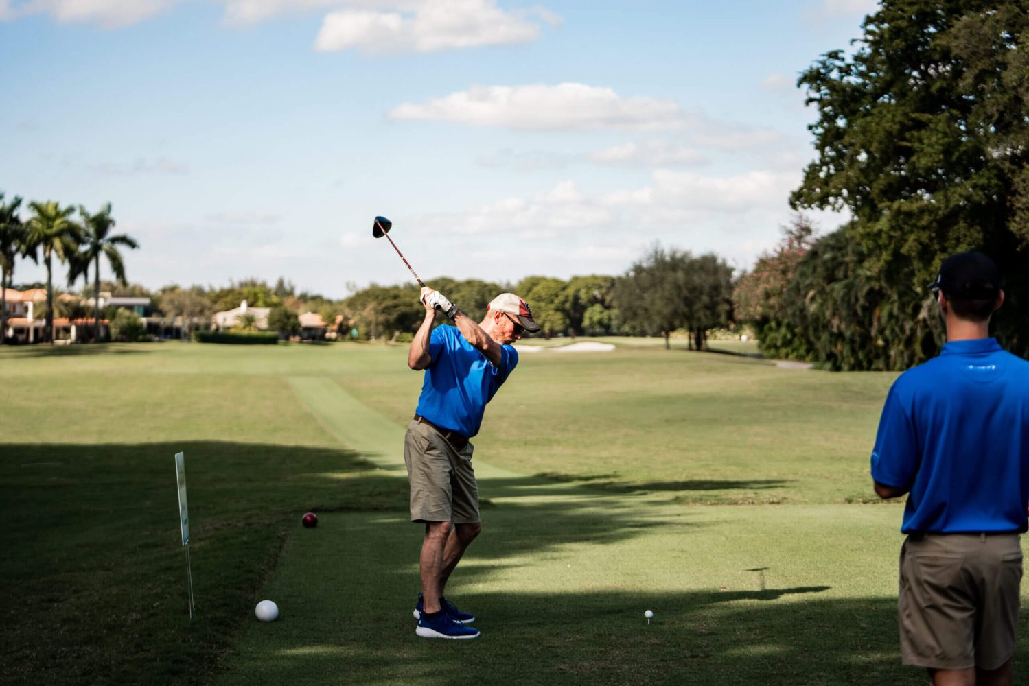 A man swinging at a golf ball on the green.