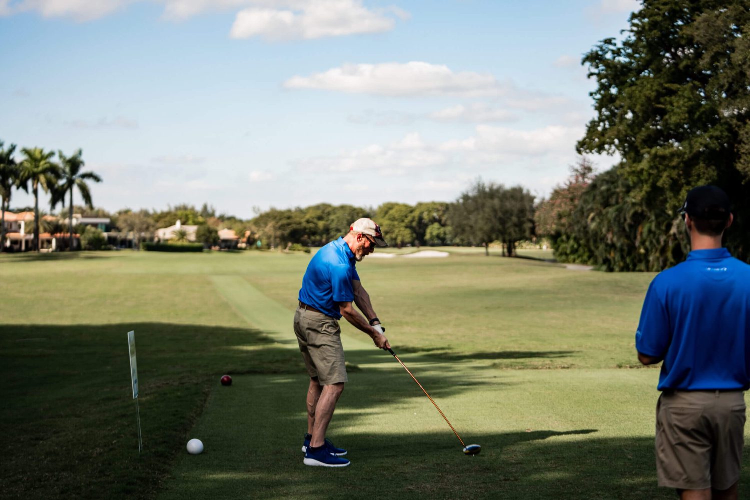 A man swinging at a golf ball on the green.