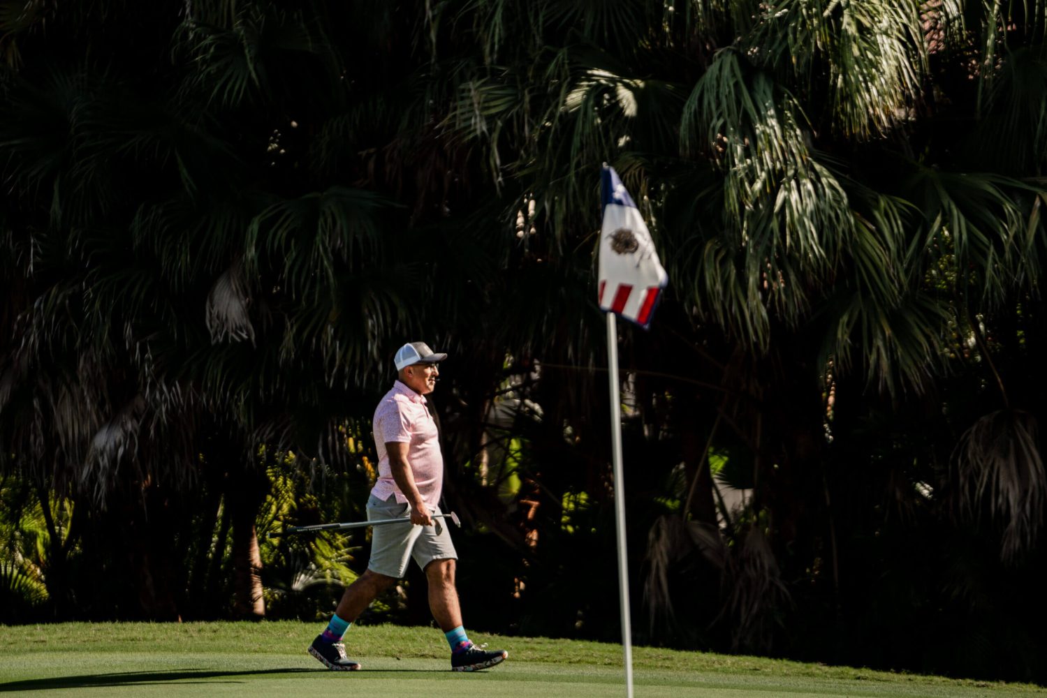 A man walking on the grass near a flag.