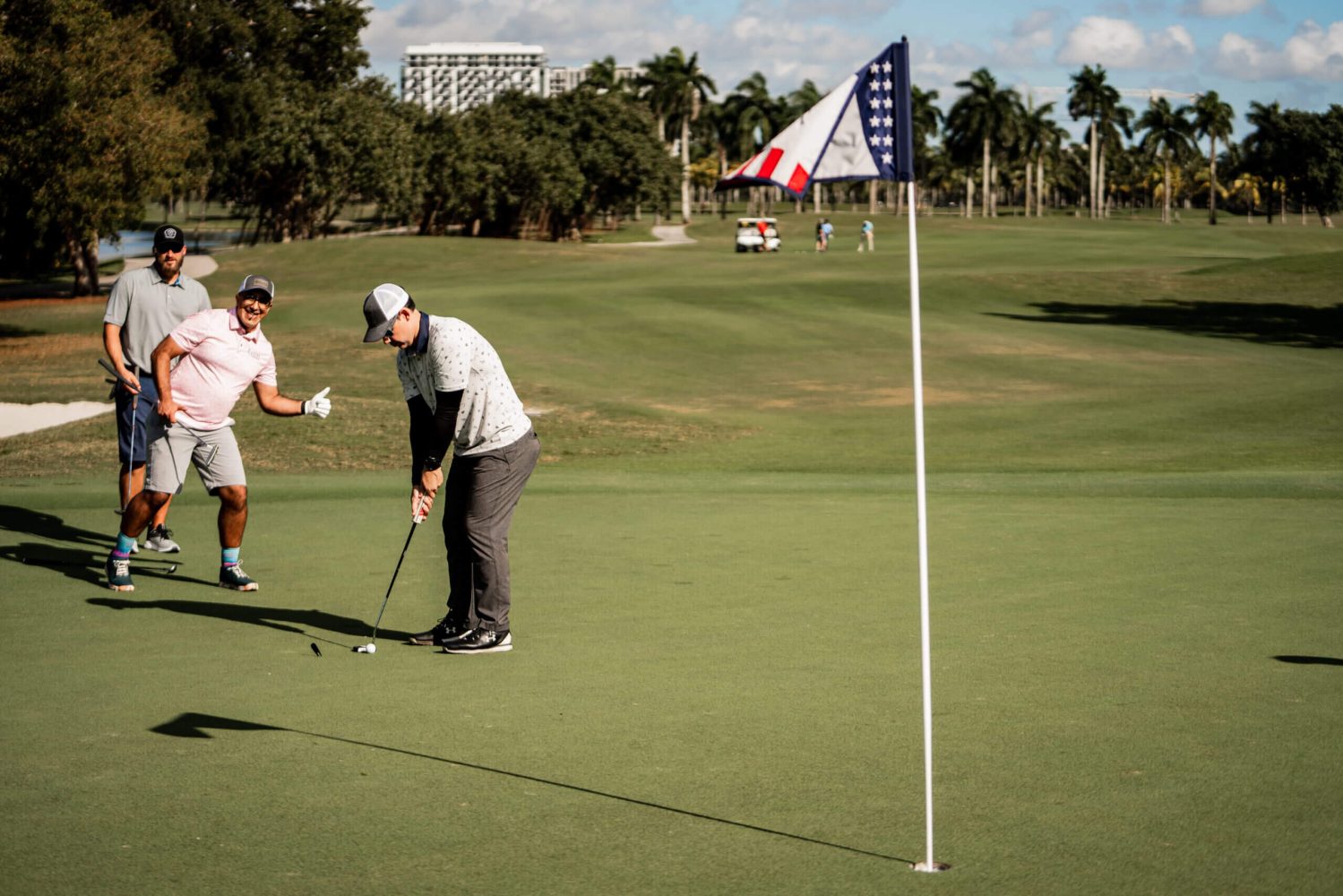 Two men playing golf on a green with trees in the background.