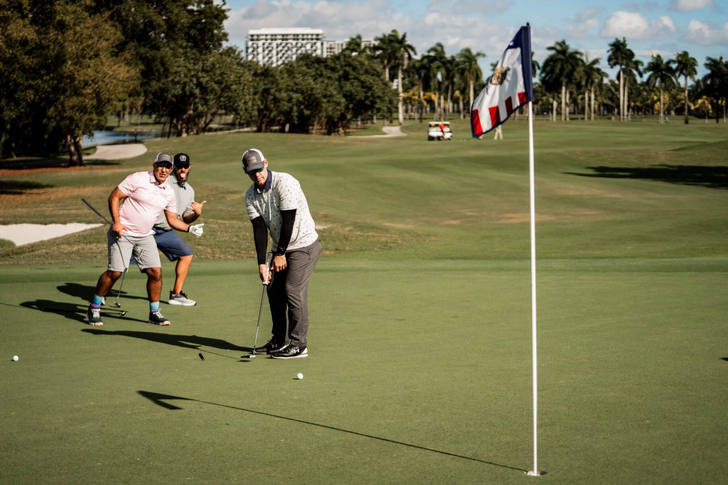 A group of people playing golf on the green.