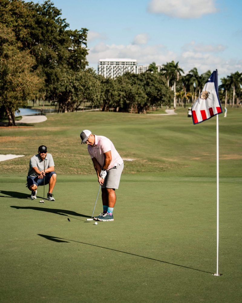 Two men are playing golf on a green.