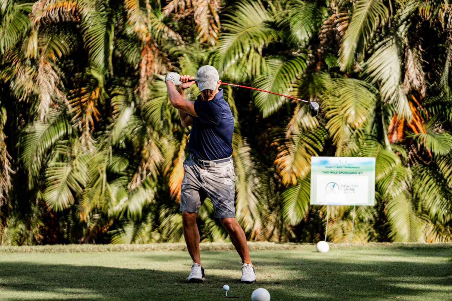 A man swinging at a golf ball on the green.