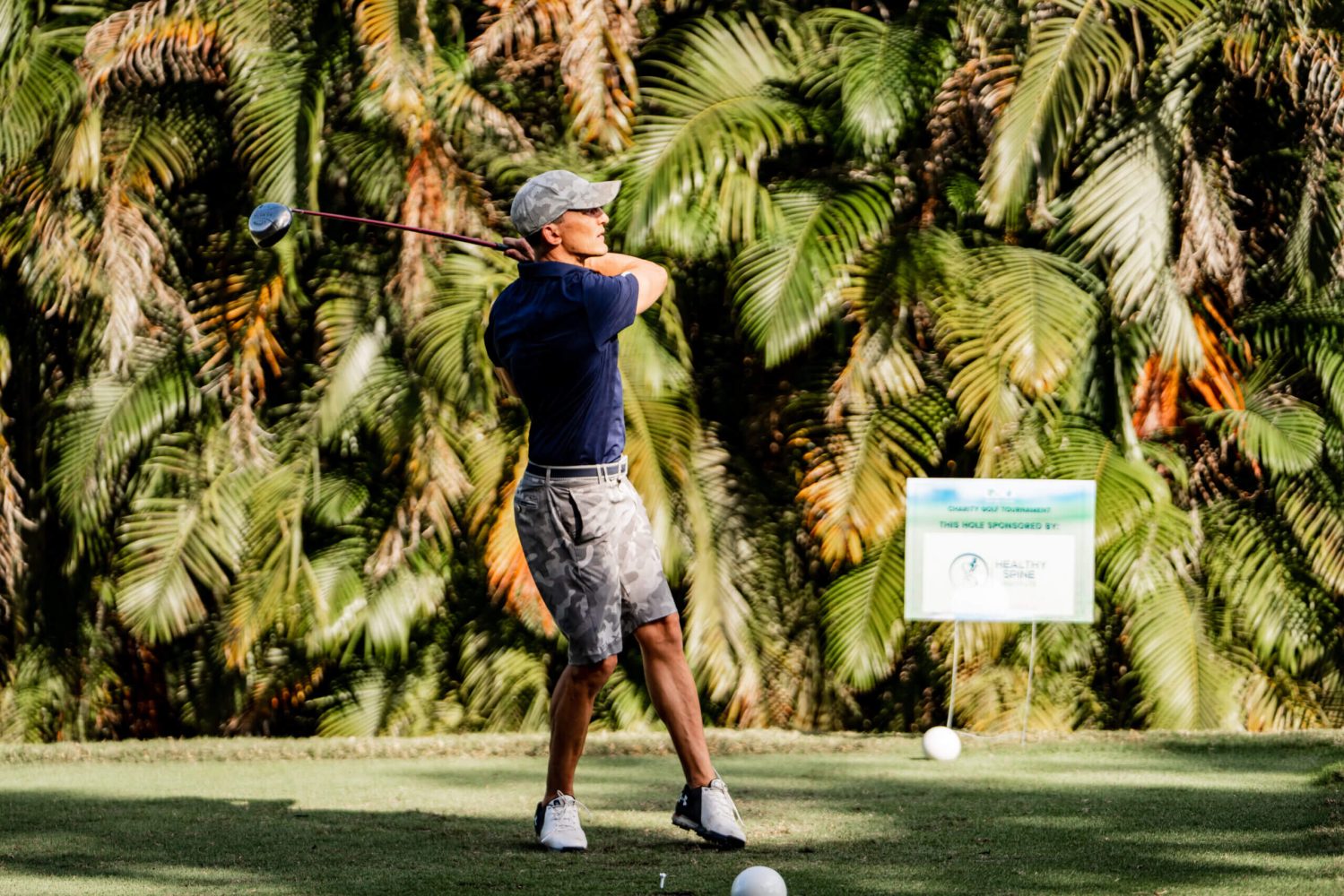A man swinging at a golf ball on the green.