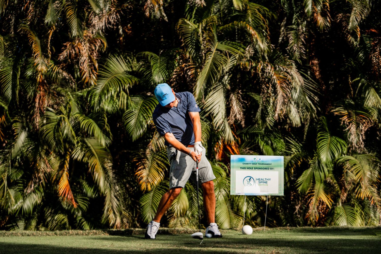 A man swinging at a golf ball on the green.