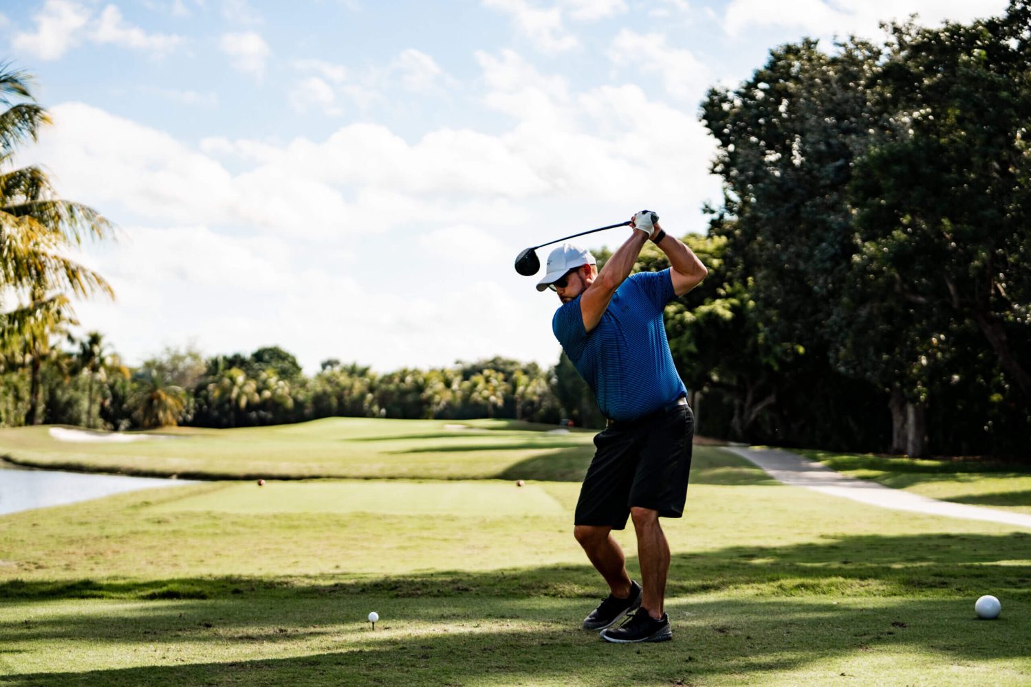 A man swinging at the ball on a golf course.