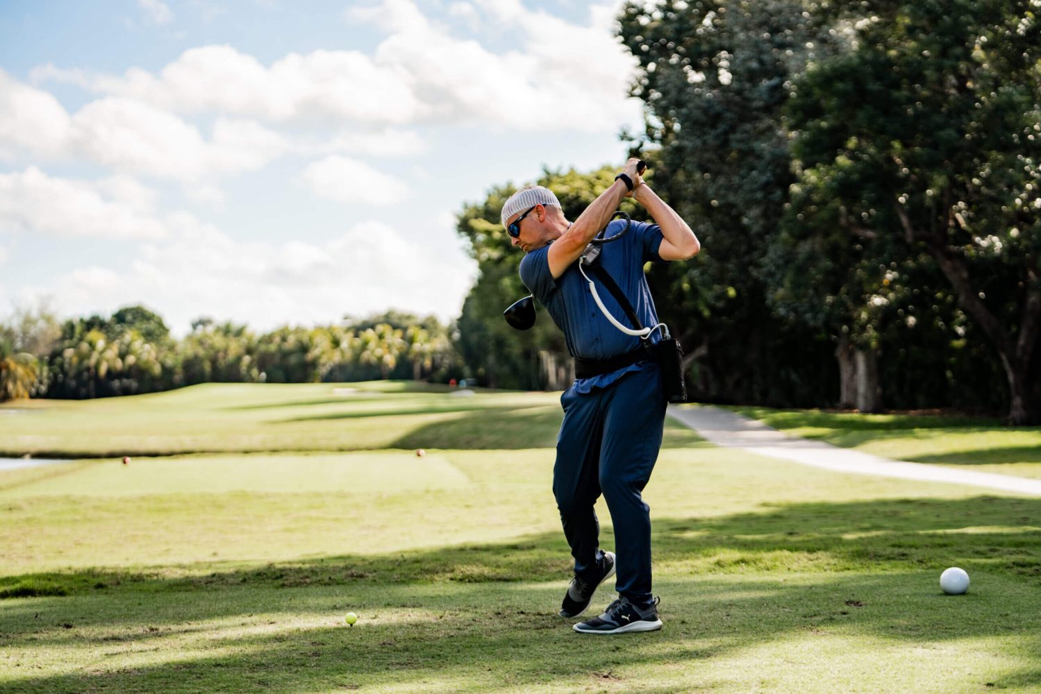 A man swinging at the golf ball on a course.