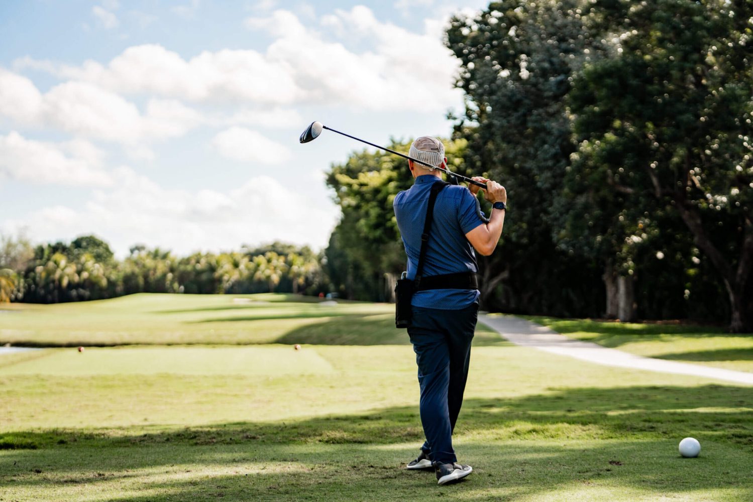 A man holding onto a golf club while standing on the grass.