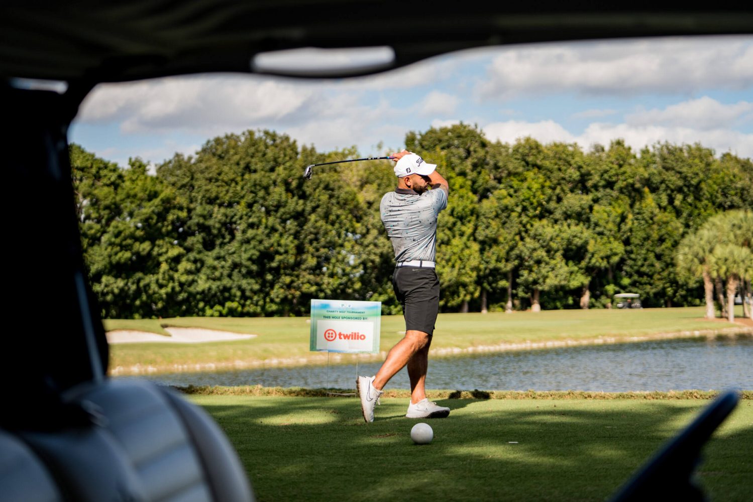A woman swinging at a golf ball on the course.