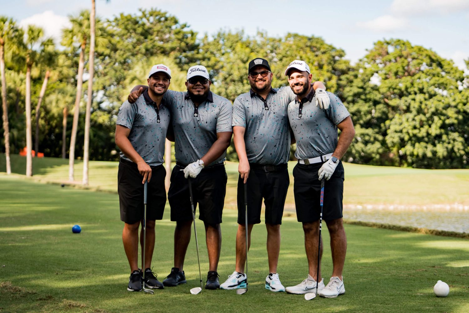 Four men standing on a golf course holding their clubs.
