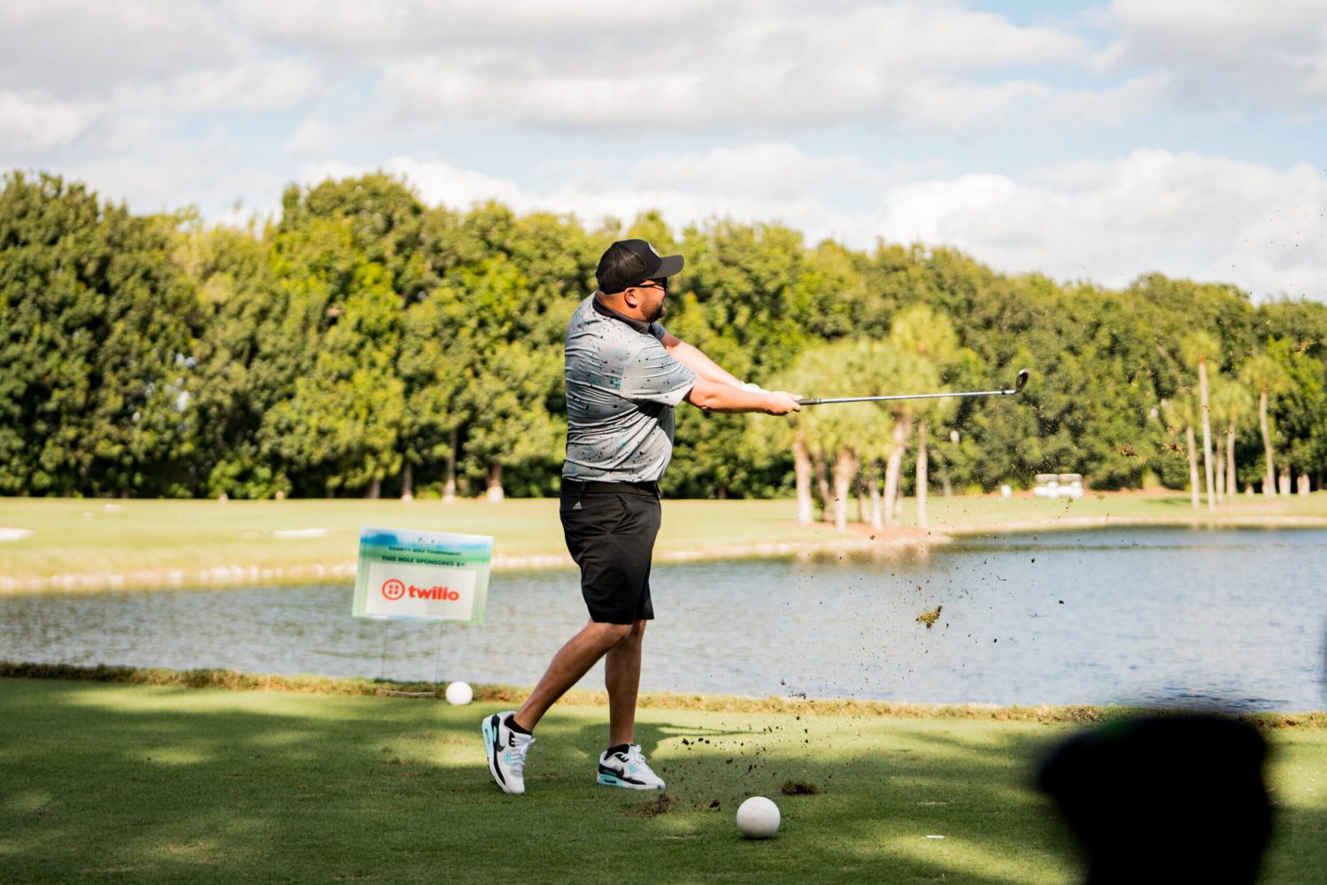 A man swinging at a golf ball on the green.