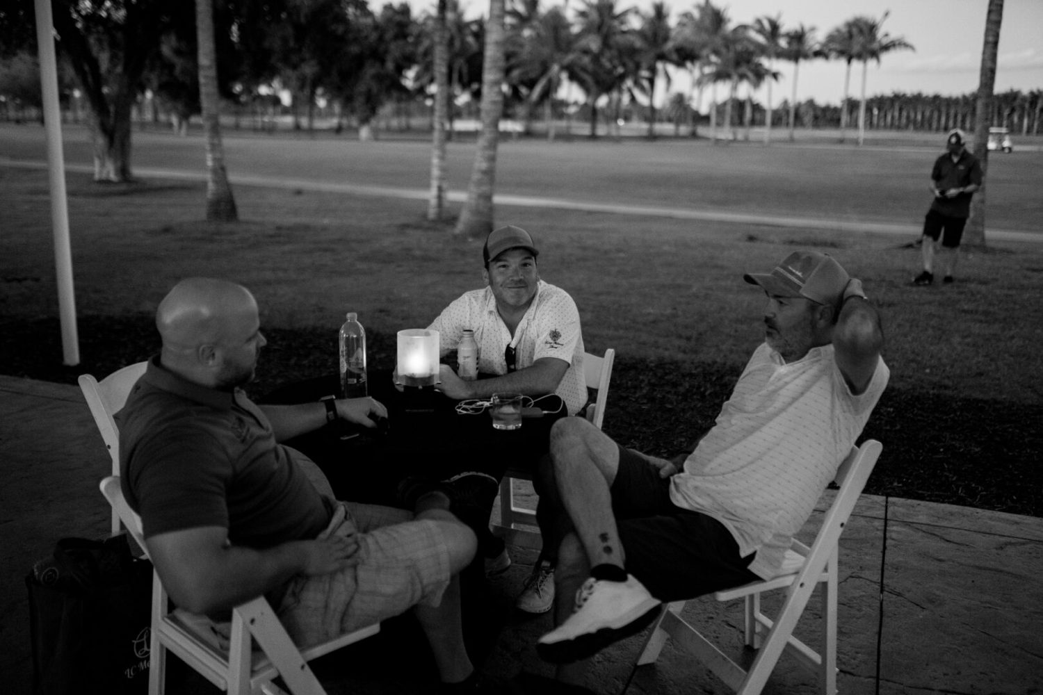 Three men sitting in lawn chairs talking to each other.