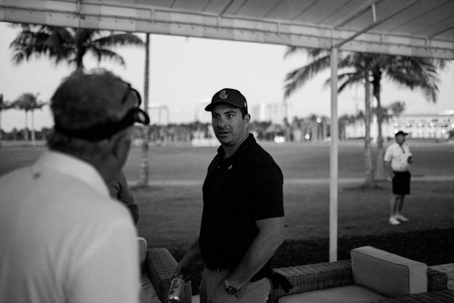 A man in black shirt and hat standing next to another person.