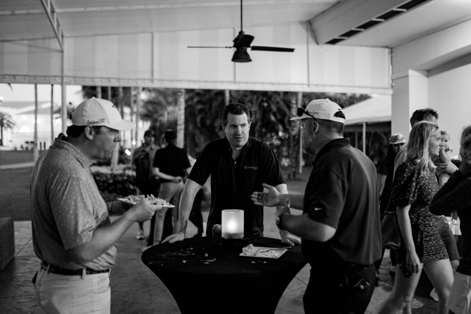 Three men standing around a table with cards.