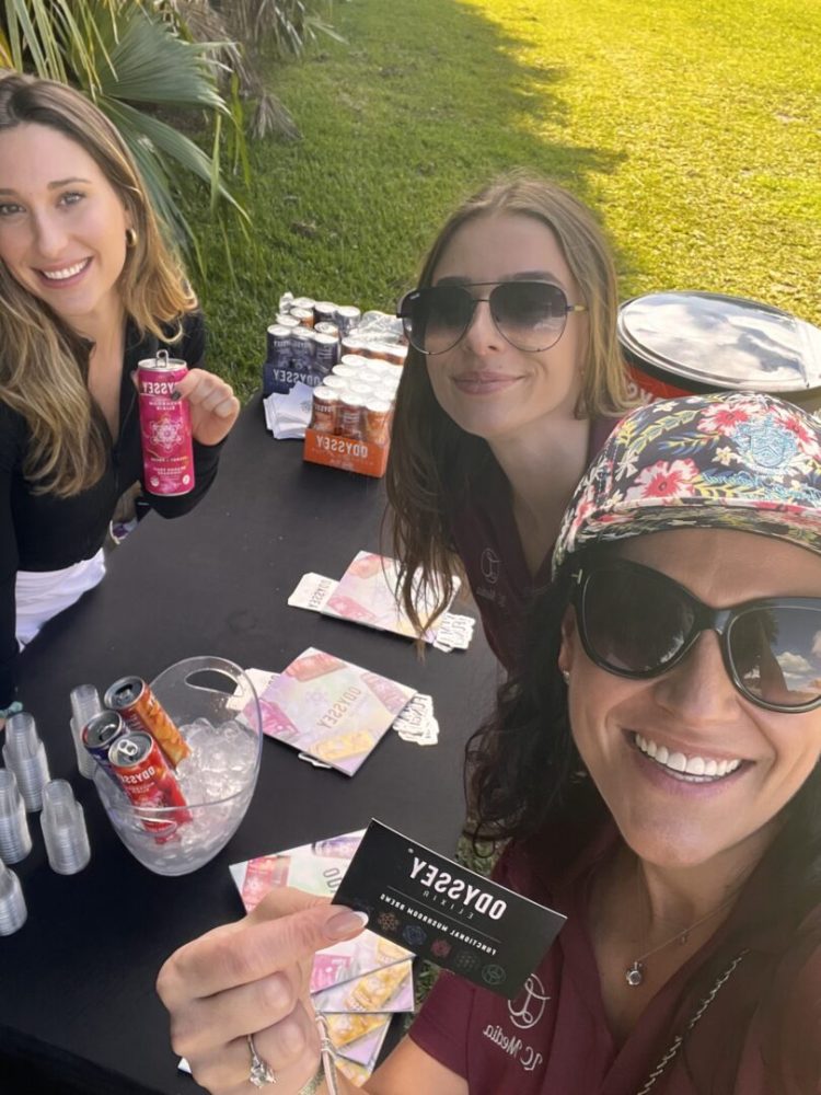 Three women sitting at a table with drinks and money.