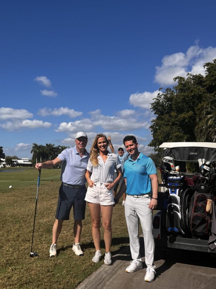 Three people standing next to a golf cart.