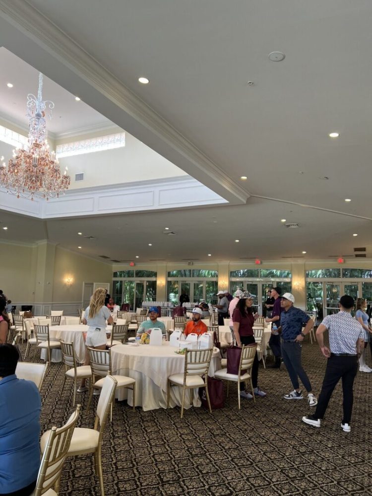 A group of people standing around tables in a room.