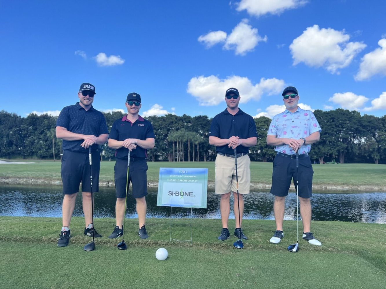 Four men are standing on a golf course.