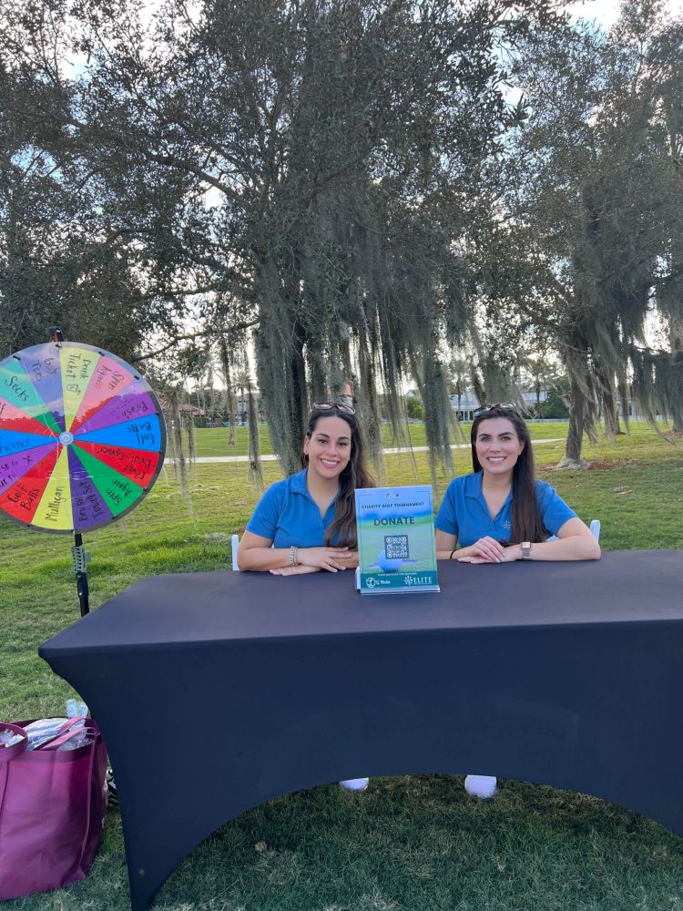 Two girls sitting at a table with a book.