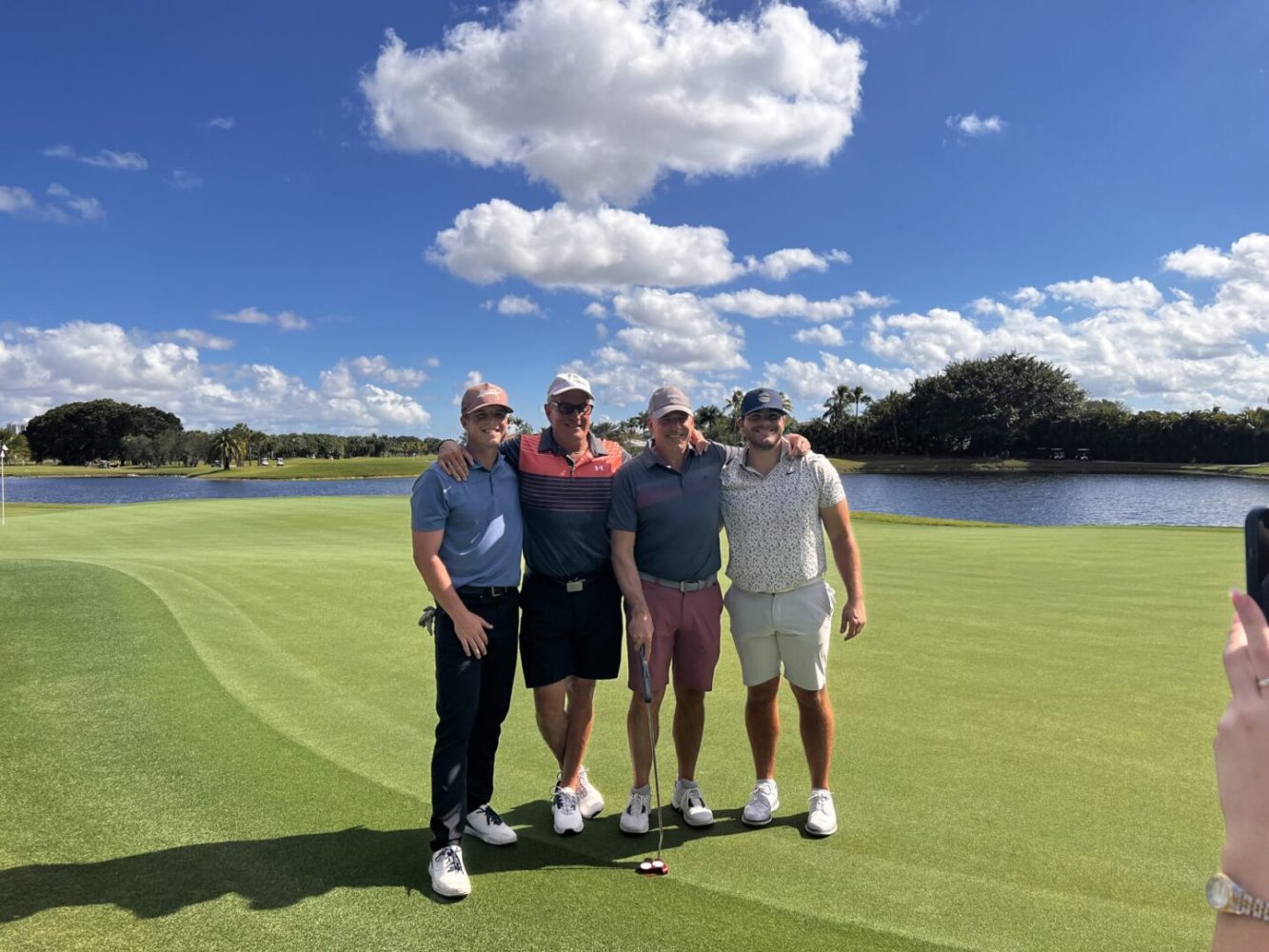 Four men standing on a golf course with one holding onto the ball.