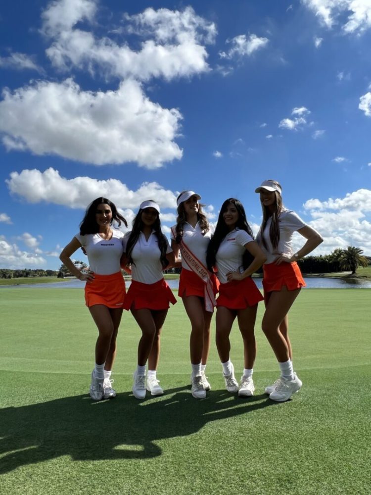 A group of women standing on top of a green field.