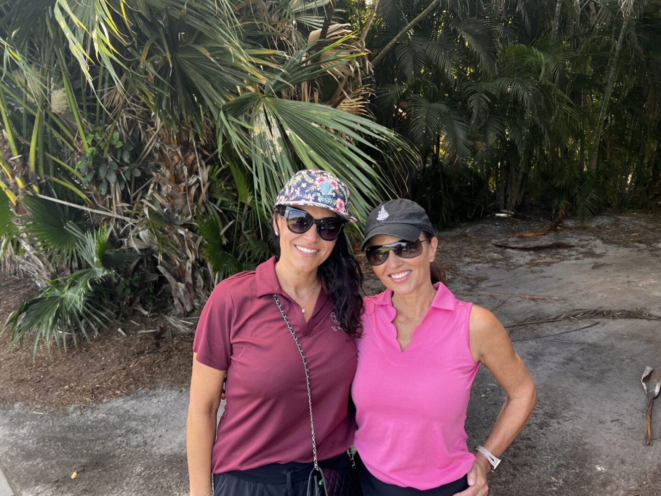 Two women standing next to each other in front of a tree.