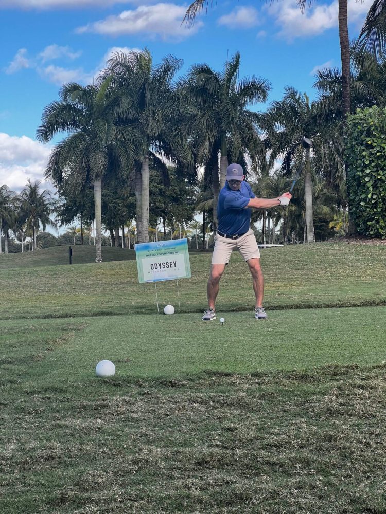 A man swinging at a golf ball on the course.