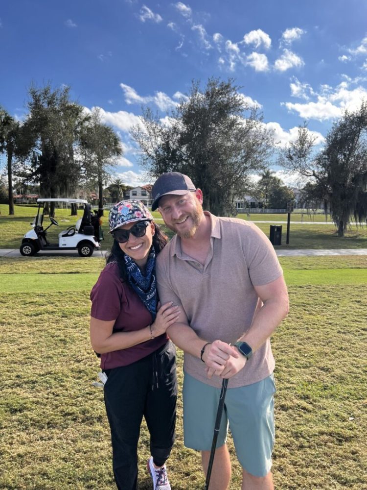 A man and woman posing for the camera while holding onto golf clubs.