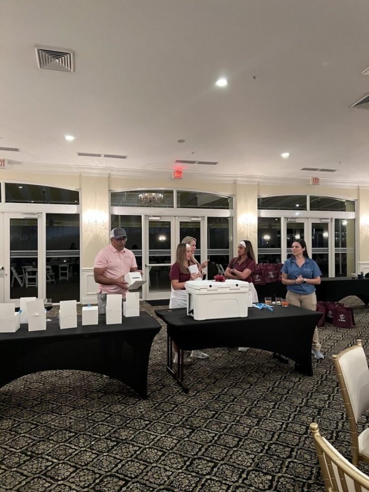 A group of people standing around tables with boxes.